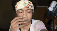 a man wearing a headband with flowers on it is drinking from a glass