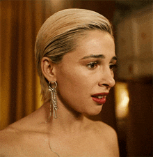 a woman without a shirt is wearing a pair of earrings