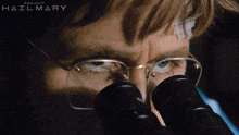 a close up of a man looking through a microscope with project hailmary written on the bottom
