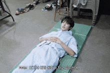 a young boy is laying on a green mat with a belt around his waist that says keiju on it