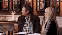 a man and a woman are sitting at a table with a starbucks drink in their hand .