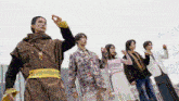 a group of people are standing next to each other with their arms in the air