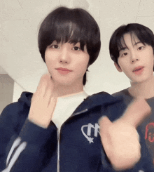 two young men are posing for a picture and one of them is wearing a blue hoodie with a heart on it
