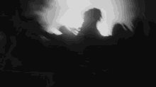 a black and white photo of a crowd of people dancing in a dark room .