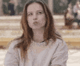 a young woman is blowing a kiss while wearing a white sweater