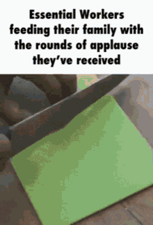 a person is cutting a piece of green paper with a knife .