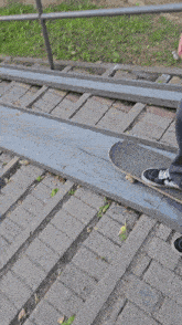 a person is riding a skateboard on a sidewalk with a fence in the background