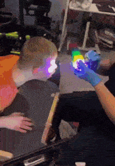 a person in a blue glove is holding a rainbow colored object in front of a child 's head