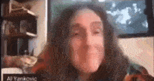 a woman with long hair is making a funny face while sitting in front of a computer screen .