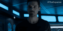 a man in a black shirt is standing in a dark room with #theexpanse written on the bottom
