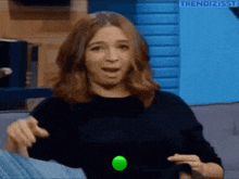a woman is sitting on a couch playing with a green ball .