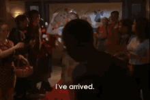 a woman wearing a tiara says i 've arrived while standing on a red carpet