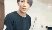 a young man is standing in a kitchen wearing a black t-shirt with the word indigo on the sleeve .
