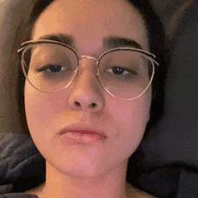 a close up of a woman wearing glasses with a sad look on her face