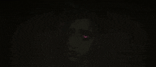 a close up of a woman 's face with glowing red eyes in the dark .