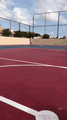 a red and blue basketball court with a fence surrounding it