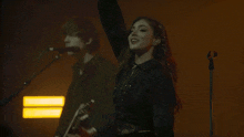 a woman is singing into a microphone while a man plays a guitar