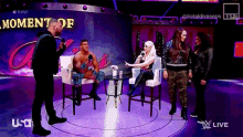 a group of people sitting in chairs on a stage with a sign that says " moment of "