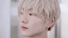 a close up of a person 's face with white hair and earrings