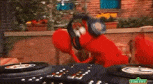 elmo from sesame street is wearing headphones and playing records .