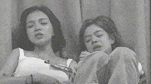 a black and white photo of two women sleeping next to each other on a bed .