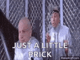 two bald men are standing next to each other in front of a fence and talking .