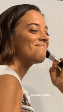 a woman is getting her makeup applied by a person with the year 2018 on the bottom