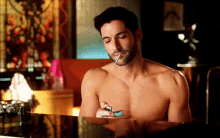 a shirtless man is lighting a cigarette with a lighter