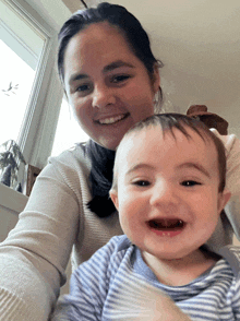 a woman is holding a baby who is smiling