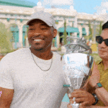 a man in a white shirt is holding a silver trophy and smiling