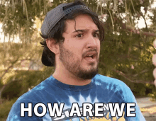 a man wearing a tie dye shirt and a hat says " how are we "