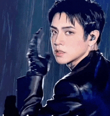 a young man wearing a black leather jacket and gloves is pointing at something .