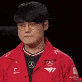 a man wearing glasses and a red jacket is making a thumbs up sign .