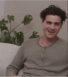 a man with curly hair is sitting on a couch smiling