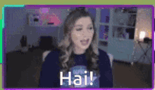 a woman wearing headphones is sitting in front of a computer screen with the words `` hai ! '' written on it .