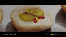 a video of a hot dog with pickles and ketchup is being played