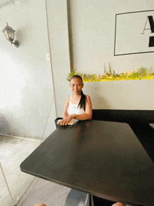 a woman sits at a table in front of a sign that says a on it
