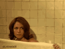 a woman peeking out from behind a towel in a bathroom with the hashtag laamed05