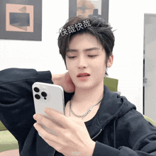a man with chinese writing on his hair is looking at his cell phone