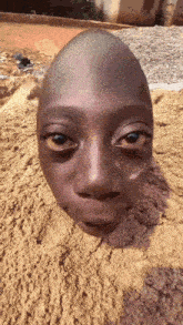 a close up of a person 's head laying in the sand