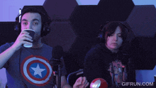 a man wearing a captain america shirt is holding a cup in front of a microphone