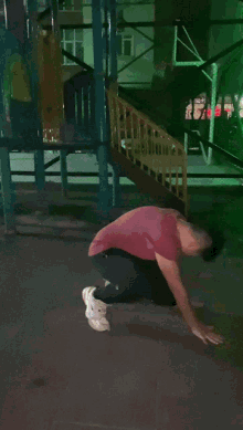 a man in a red shirt is doing push ups in a park