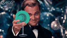 a man in a tuxedo is holding a green circle in front of his face and the word eco is on the bottom