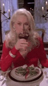 a woman is sitting at a table drinking a glass of red wine
