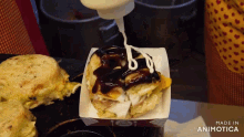 a person is pouring mayonnaise on a sandwich in a cardboard box that says made in animatica