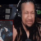a man wearing headphones is sitting in front of a microphone and making a funny face .