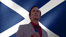 a man in a suit and tie stands in front of a flag