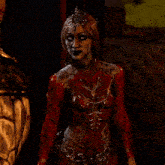 a woman in a red bodysuit with chains around her waist and a crown on her head
