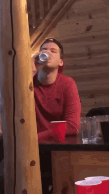 a man in a red sweater is sitting at a table with red cups