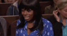 a woman in a blue shirt is sitting in a row of people .